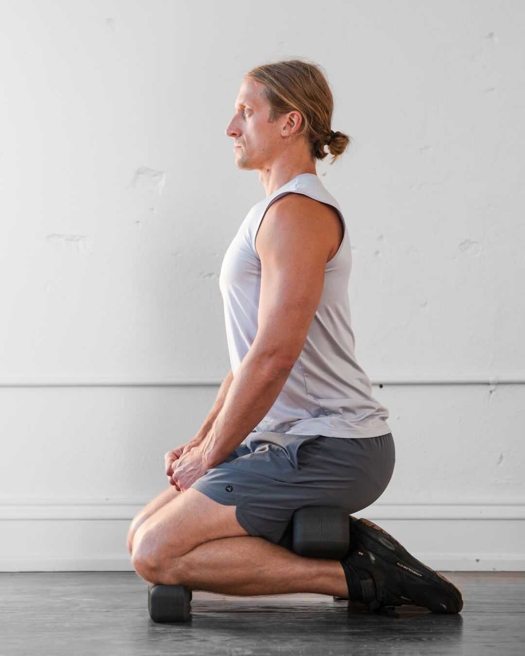 person kneeling on a mini (un)block with another (un)block between calves and hamstrings